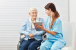 Pflegekraft erklärt einer Seniorin einen Tablet PC
