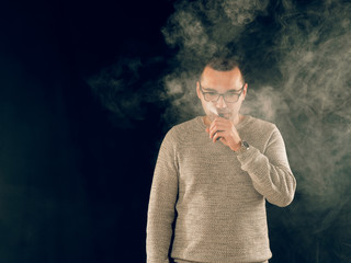 smoking man in e-cigarette smoke on black background