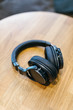 Photo of black wireless headphones on wooden table/ high-quality expensive headphone, natural materials, music time, selective focus on headset, top view with copy space/ music and lifestyle concept.