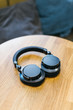 Photo of black wireless headphones on wooden table/ high-quality expensive headphone, music lover, music time, selective focus on headset, top view with copy space/ music and lifestyle concept.