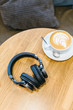 Picture of black wireless headphones and white cup of coffee on wooden table/ listening music with headphone, music time, flat lay, headset, top view with copy space/ music and lifestyle concept.