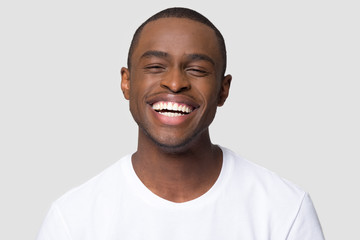 cheerful happy african millennial man laughing looking at camera isolated on studio blank background