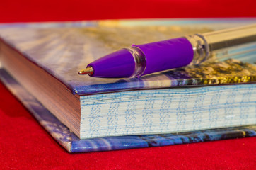 Pen and notebook closeup on a red background.