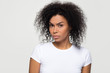 Suspicious annoyed young african american woman with distrustful face looking at camera, skeptical sarcastic black girl feeling cautious dubious distrusting isolated on grey white studio background