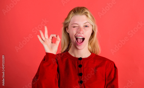 Fotomural Girl wink happy face while show ok gesture over red background