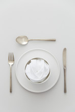 Minimal Grey And White Table Setting With A Brass Cutlery Set, A Plate And A Bowl With A White Napkin.