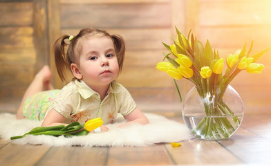 A small child with a bouquet of yellow tulips. A boy with a gift of flowers in a vase. A gift for girls on a female holiday with yellow tulips on the floor.