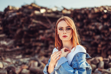 Portrait of young tender redhead young girl with healthy freckled skin wearing white top looking at camera with serious or pensive expression. Caucasian woman model with ginger hair posing outdoors