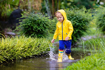 Wall Mural - Kids in puddle in autumn rain. Waterproof wear