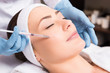 © LIGHTFIELD STUDIOS - beautician making injection face attractive woman at beauty salon