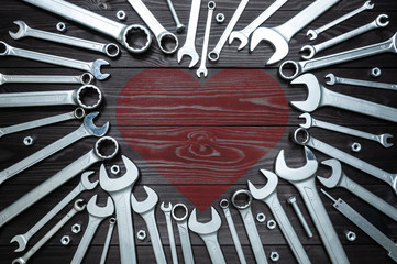 wrenches and heart on dark wooden background. Concept love for their work.