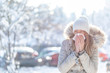 Young woman coughing during winter on street. Girl with cold wearing knitted cap and scarf feeling unwell. Woman feeling sick during for winter and city pollution. Girl with sore throat.
