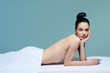 © LUMINA IMAGES - Portrait of beautiful naked Caucasian woman brunette lying on massage table at salon and looking at camera.