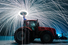 Man Sparks On The Background Of A Red Tractor, Steel Wool Photo, Sparks On A Long Exposure,