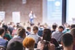 © Feel good studio - Adult students listen to professor's lecture in class room, hands up for queue of asking question to Lecturer or poll voting.  Rear view, Audience Watching a Presentation. Business, education.