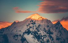 Mountain Top Colorful Sunet, Antarctica. The Sunlit Snow Covered Range. Breathtaking Polar Scenery. The Mighty Mountain Range Under The Bright Sunset Cloudy Sky. Amazing South Pole Landscape.