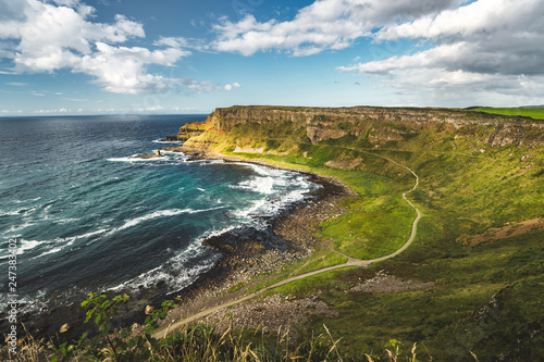 Northern Ireland Shoreline Overview Breathtaking Irish Landscape The Grass Covered Land Next To The Ocean Tourist Trail For Hiking In The National Park Blue Cloudy Sky Background Horizon View Buy This