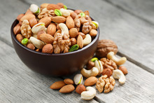 Wooden Bowl With Mixed Nuts On A Wooden Gray Background. Walnut, Pistachios, Almonds, Hazelnuts And Cashews, Walnut.