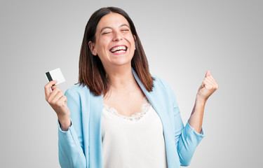 Middle aged woman cheerful and smiling, very excited holding the new bank card, ready to go shopping