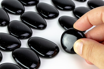 Black pebbles on white background with brown pebble.