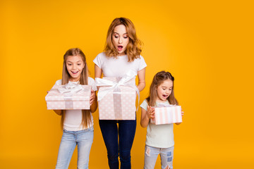 Poster - Portrait of three nice cute lovely winsome attractive cheerful positive curious impressed funny people holding in hands boxes great day isolated over bright vivid shine yellow background