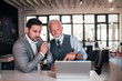 © bnenin - Image of a handsome young and senior business executives discussing something on laptop in the office.
