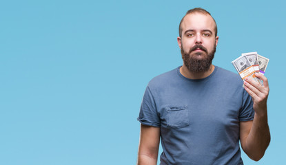 Poster - Young hipster man holding bunch of money over isolated background with a confident expression on smart face thinking serious