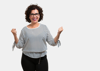 Middle aged woman very happy and excited, raising arms, celebrating a victory or success, winning the lottery