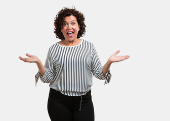 Middle aged woman screaming happy, surprised by an offer or a promotion, gaping, jumping and proud