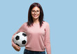 © Asier - Young pretty woman smiling and happy, holding a soccer ball, competitive attitude, excited to play a game