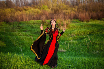 beautiful, young girl in black and red medieval dress with crown on head.