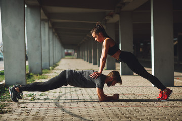 Wall Mural - Young sports couple exercising in the urban environment