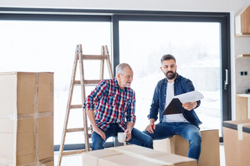 Wall Mural - A senior man helping his son with furnishing new house, a new home concept.