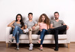 © Halfpoint - Portrait of young group of friends sitting on a sofa in a studio.