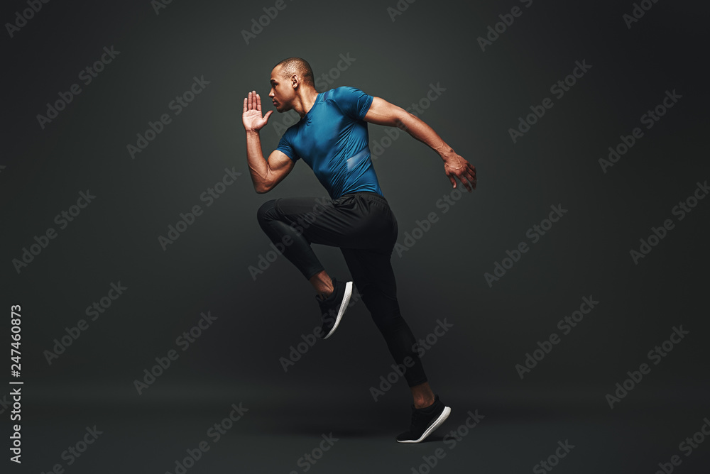 Deserve Victory. Sportsman jumping over dark background, he is ready to run - obrazy, fototapety, plakaty 