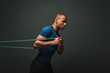 © Friends Stock - Pushing hard. Sportsman working out with resistance band over dark background