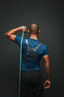 © Friends Stock - Give your best. Sportsman standing with resistance band over dark background. Back view