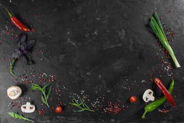 Selection of spices herbs and greens. Ingredients for cooking. Food background on black slate table. Top view copy space.