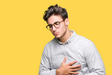 Young handsome man wearing glasses over isolated background with hand on stomach because nausea, painful disease feeling unwell. Ache concept.