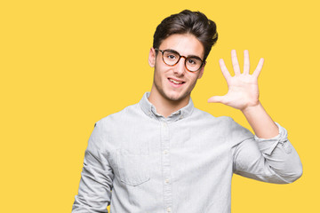 Young handsome man wearing glasses over isolated background showing and pointing up with fingers number five while smiling confident and happy.