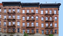 Old Brown Brick New York Apartment Building With External Fire Escape Ladders