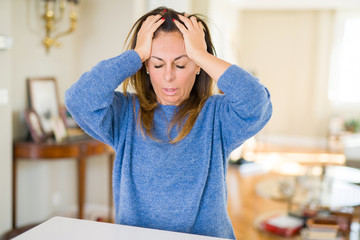 Canvas Print - Beautiful middle age woman at home suffering from headache desperate and stressed because pain and migraine. Hands on head.