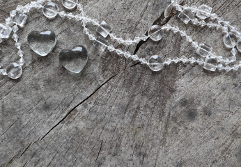 Two transparent hearts and beads on the rough surface of an old stump. Perfect Valentine's Day greeting card background.