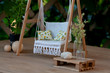 Dollhouse garden swing with white linen upholstery and pillows, A cozy sitting place for summer rest and recreation