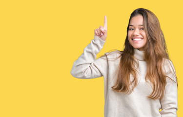 Young beautiful brunette woman wearing turtleneck sweater over isolated background pointing finger up with successful idea. Exited and happy. Number one.