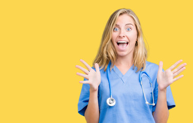 Beautiful young doctor woman wearing medical uniform over isolated background celebrating crazy and amazed for success with arms raised and open eyes screaming excited. Winner concept