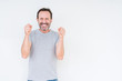© Krakenimages.com - Handsome senior man over isolated background excited for success with arms raised celebrating victory smiling. Winner concept.