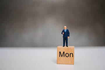 Miniature people, businessman standing on Monday block using as business concept