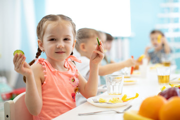 Wall Mural - Adorable kid girl eating vegetables in kindergarten