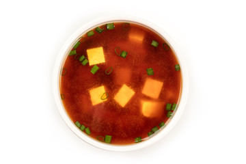 Wall Mural - A bowl of miso soup with tofu and scallions, shot from above on a white background with a place for text